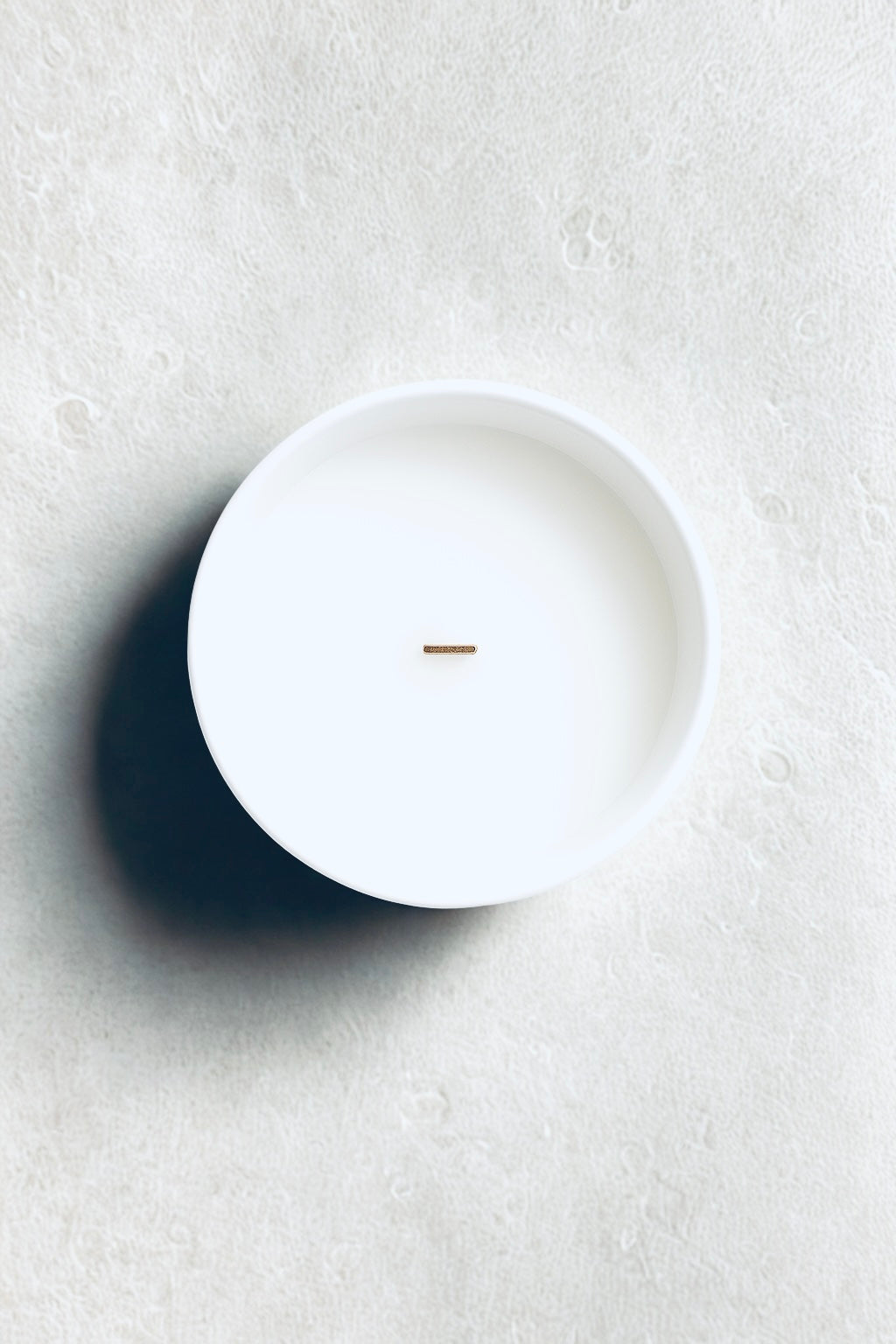 White ceramic plate on a textured white surface“Minimalist luxury winter candle UK by Aurum Blanc, hand-poured Brise des Pins premium scented candle with forest-inspired fragrance.”