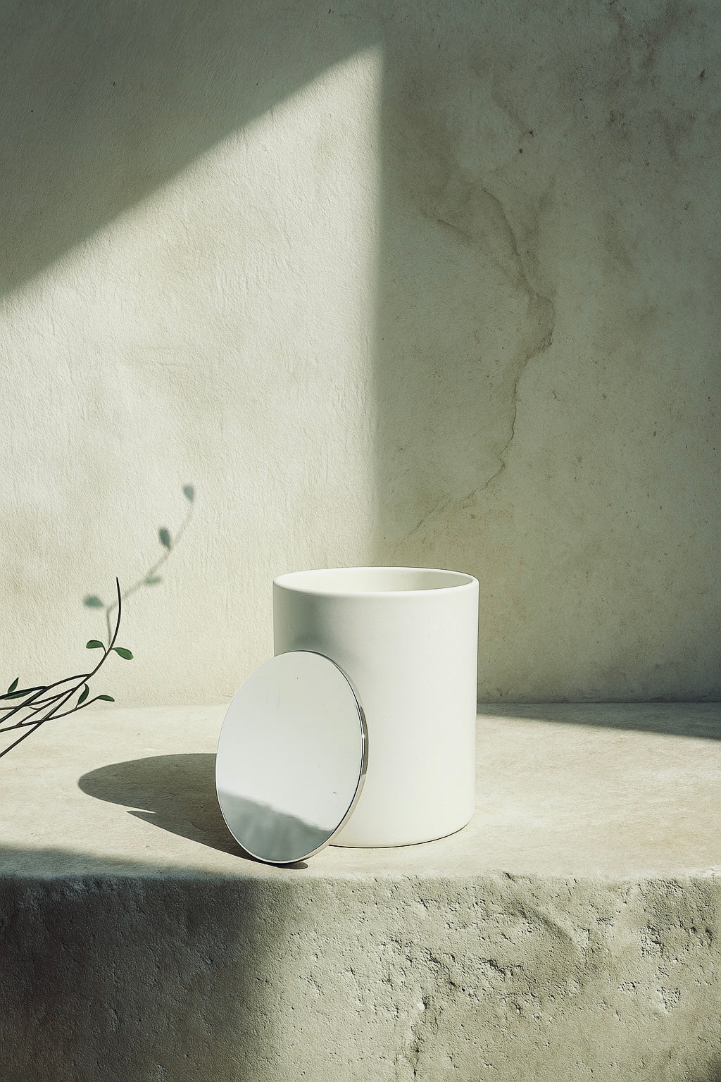 White candle on a concrete surface with a neutral background“Aurum Blanc Éclat de Noël luxury winter candle UK in white ceramic vessel with silver lid, premium scented candle with orange, cinnamon, clove and almond notes for warm winter home fragrance.”